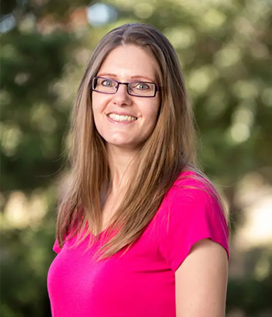 a woman wearing glasses and a pink shirt